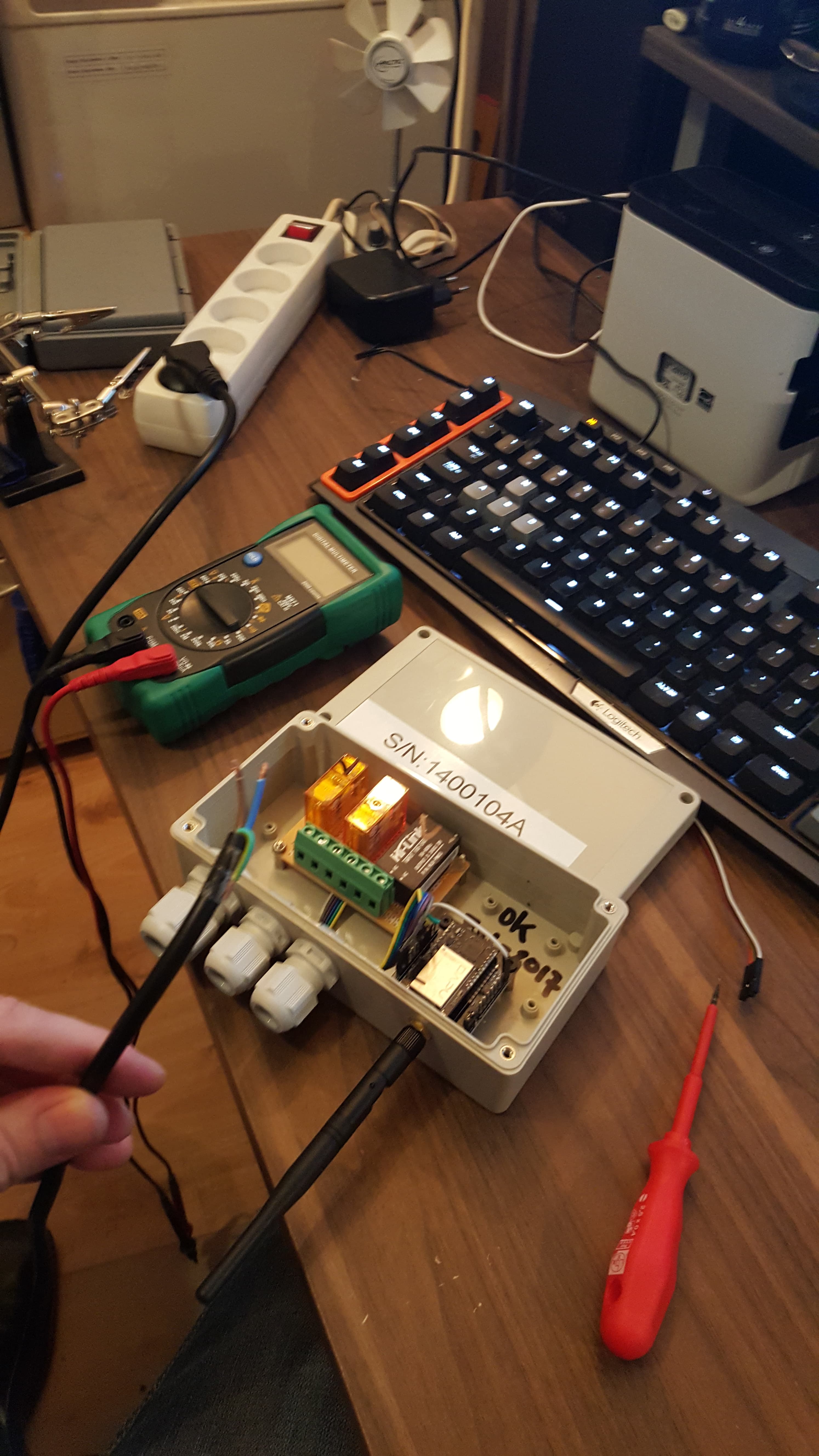 A serialized, weatherproofed unit being tested with a multimeter